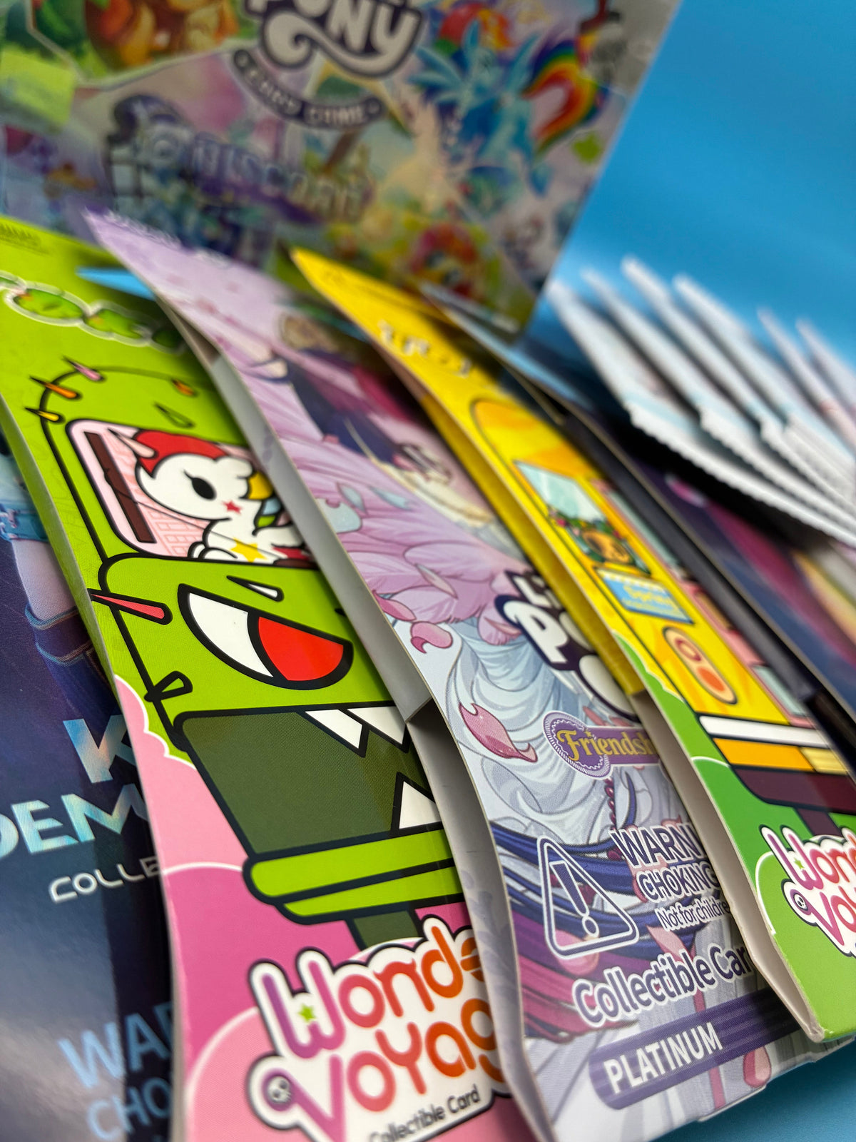 Unopened My Little Pony card packs spread across a table, the foil wrappers printed in purple and pink.